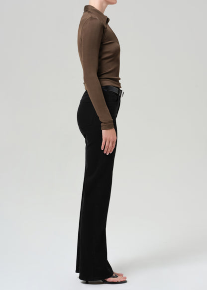 Person wearing a brown long-sleeve polo and black jeans on a grey background