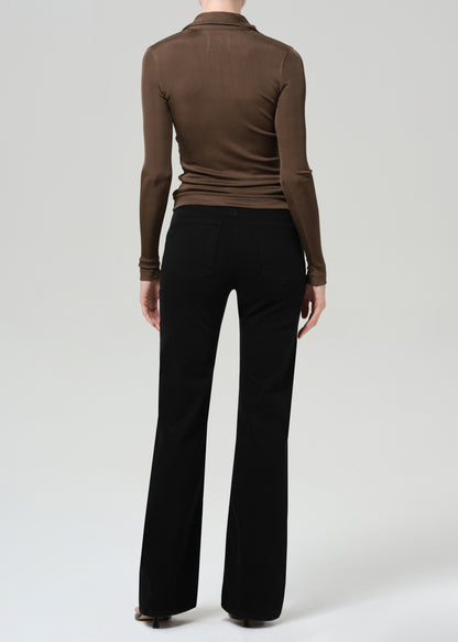 Person wearing a brown long-sleeve polo and black jeans on a grey background