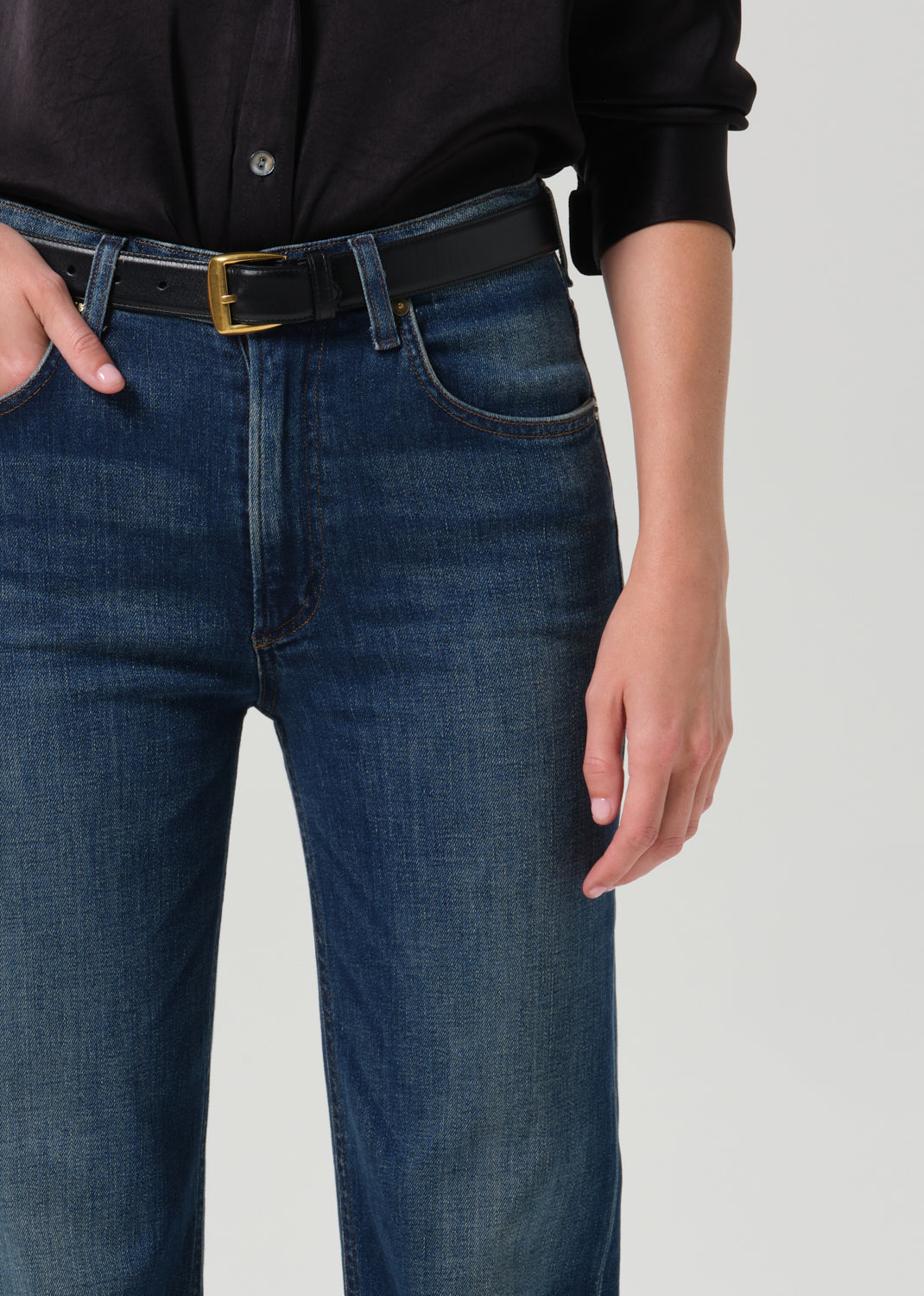 Close-up of dark indigo straight leg jeans on a grey background.