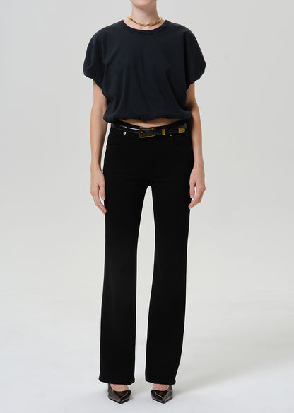 Woman wearing black straight leg pants with a black short sleeve top on a grey background.