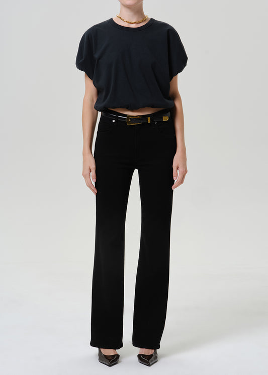 Woman wearing black straight leg pants with a black short sleeve top on a grey background.