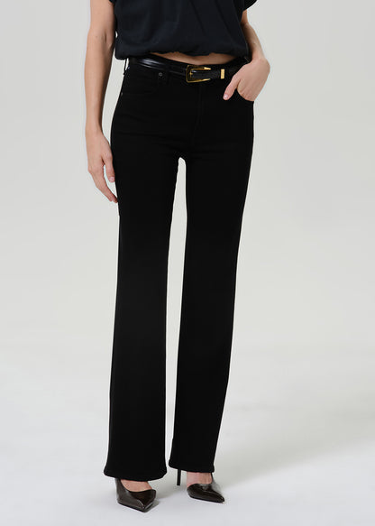 Woman wearing black straight leg pants with a black short sleeve top on a grey background.