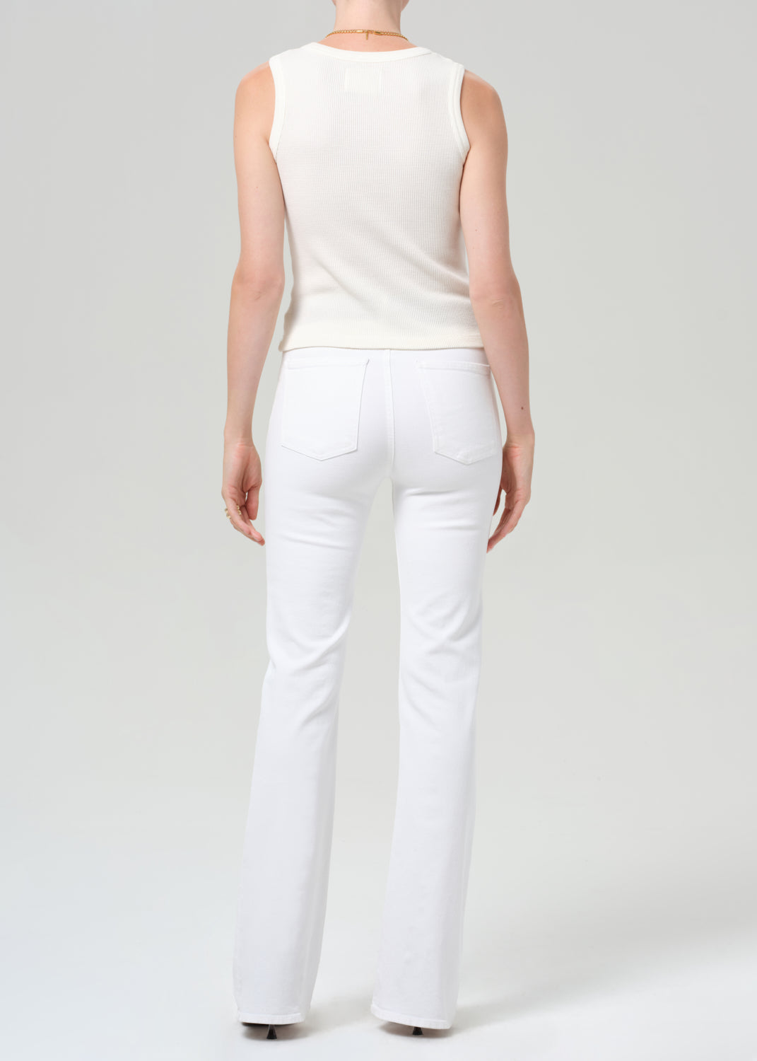 Person wearing a white sleeveless top and pants on a plain background