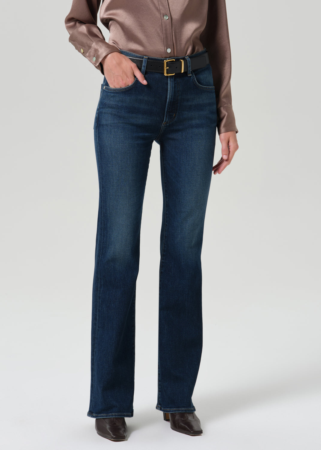 Person wearing blue jeans on a grey background