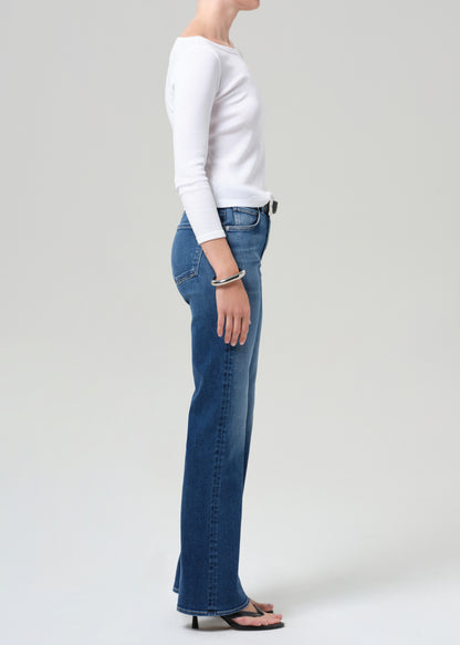 Person wearing blue jeans and a white long-sleeve shirt on a plain background