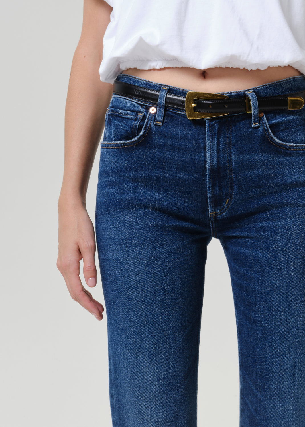 Close-up of medium blue straight leg jeans on a grey background.