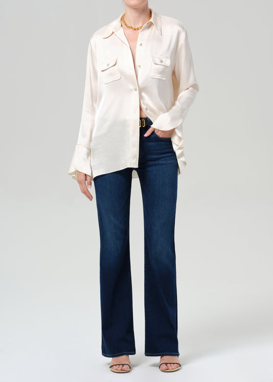 Person wearing a white blouse and blue jeans on a plain background