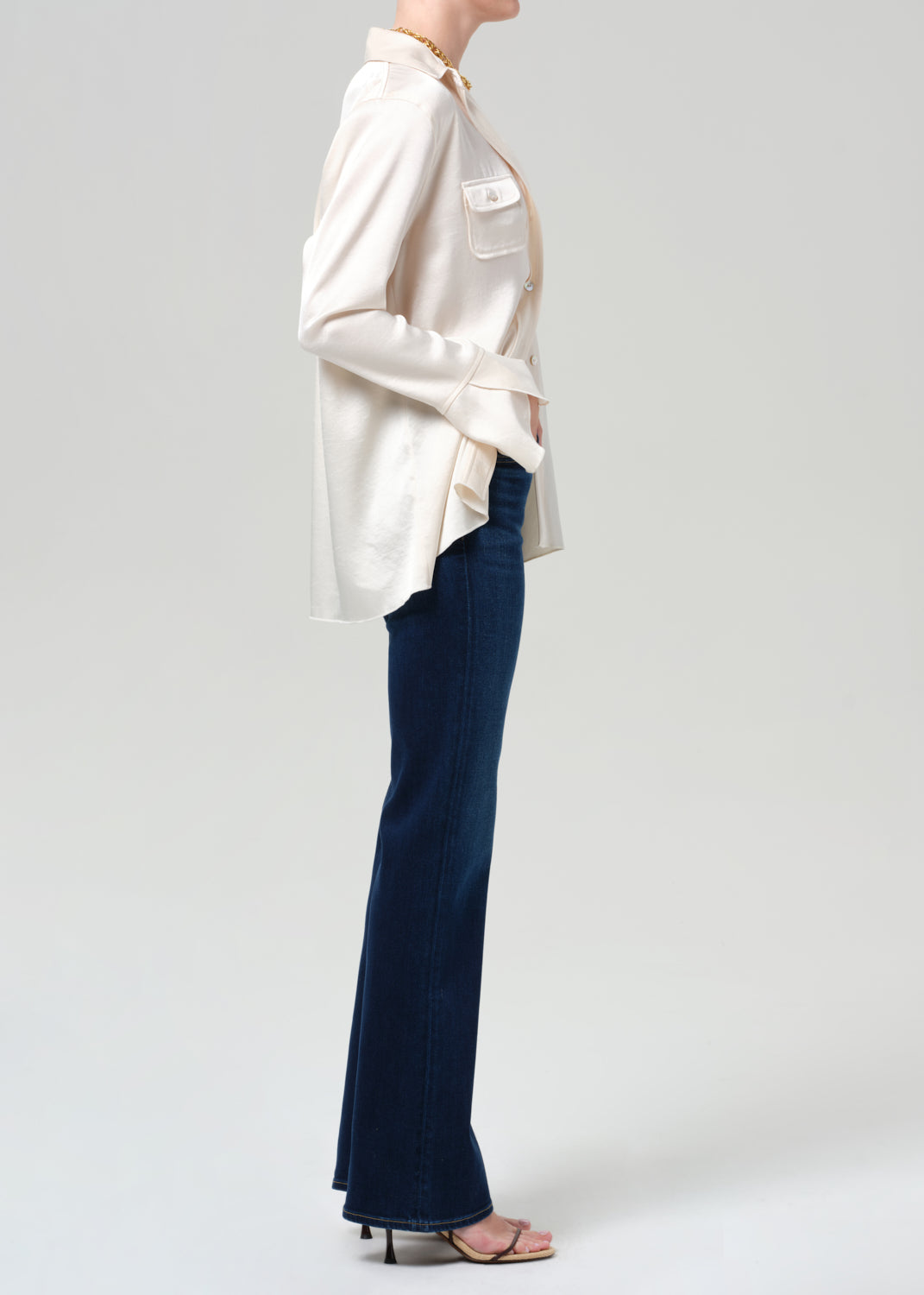 Person wearing a cream blouse and blue pants on a plain background