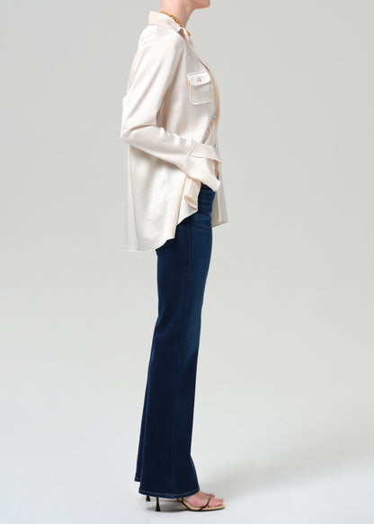 Person wearing a cream blouse and blue pants on a plain background