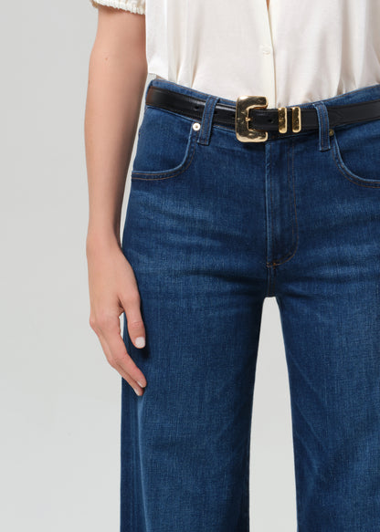 Person wearing blue jeans with a white shirt on a light gray background