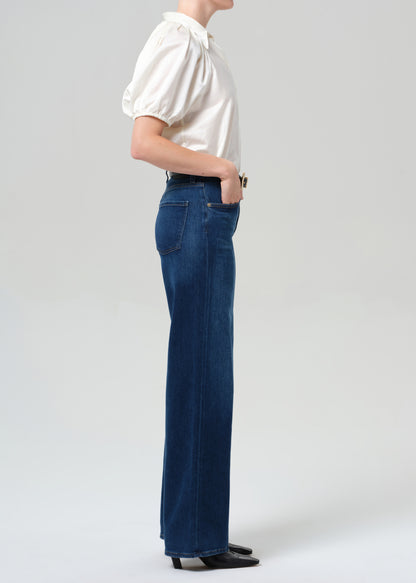 Person wearing a white shirt and blue jeans on a plain background