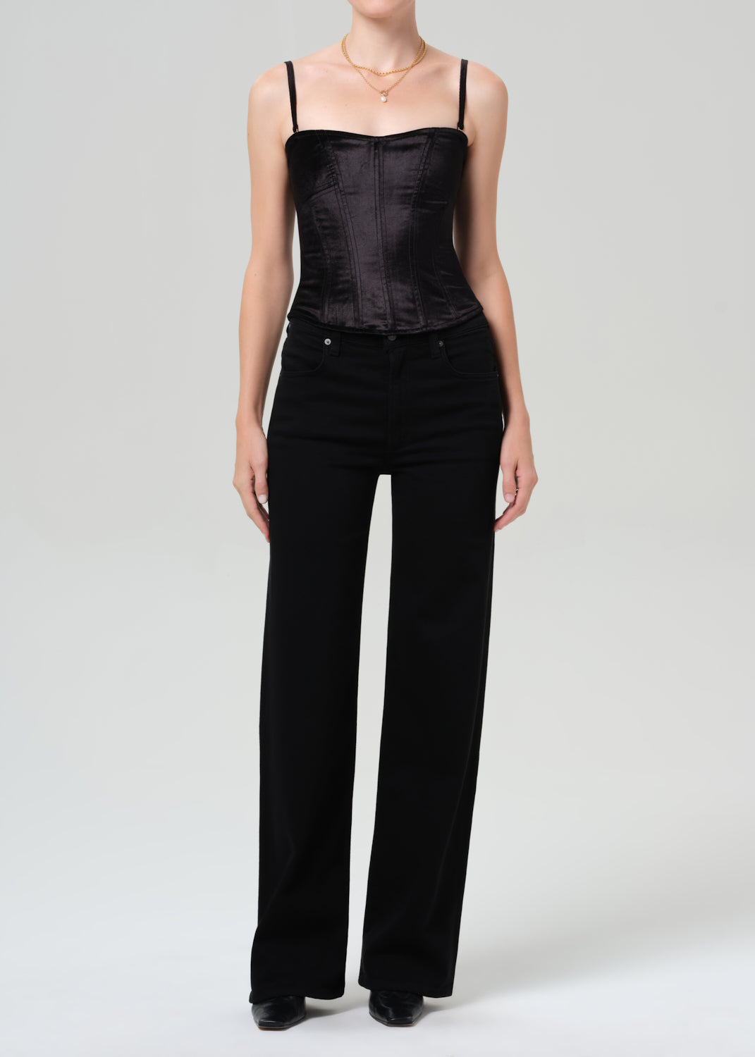 Person wearing a black top and wide-leg pants on a grey background