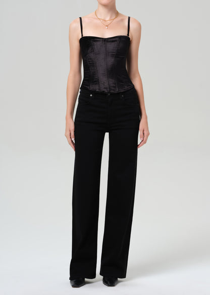 Person wearing a black top and wide-leg pants on a grey background