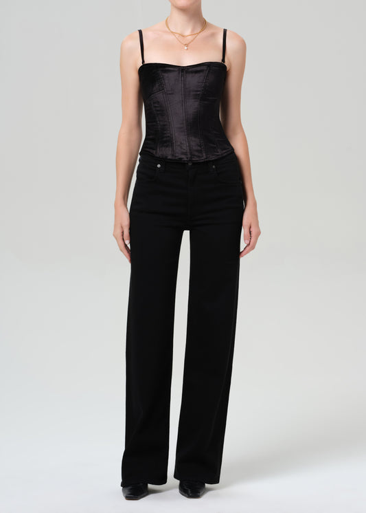 Person wearing a black top and wide-leg pants on a grey background