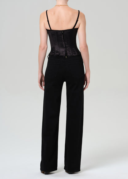 Person wearing a black top and wide-leg pants on a grey background