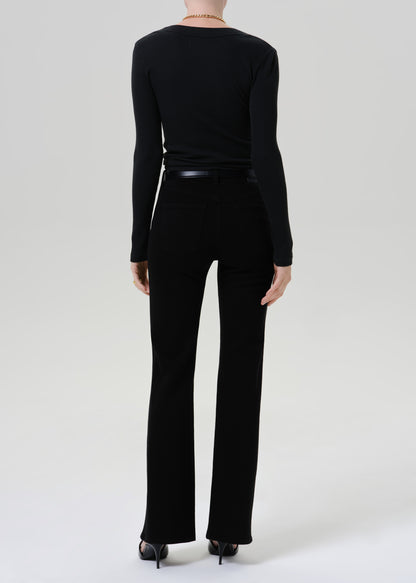A model shown from the back wearing a black long-sleeve top and black flared pants, paired with black heels, against a grey background.