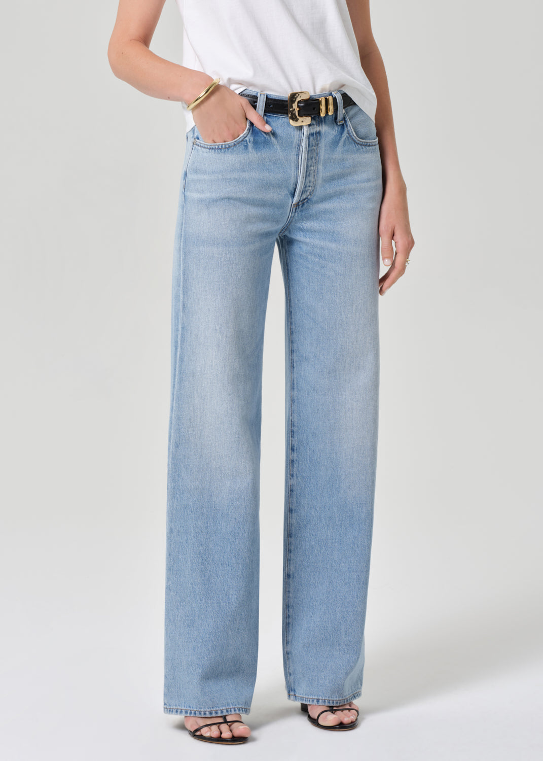 Light blue jeans worn by a person on a grey background