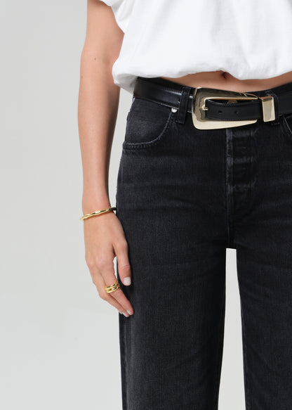 Person wearing a white top and black jeans on a plain background