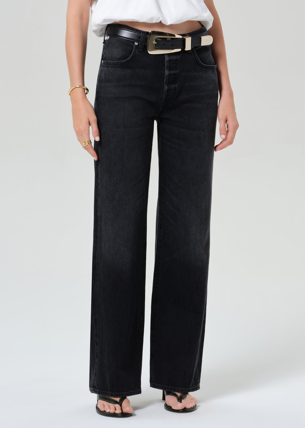 Person wearing a white top and black jeans on a plain background