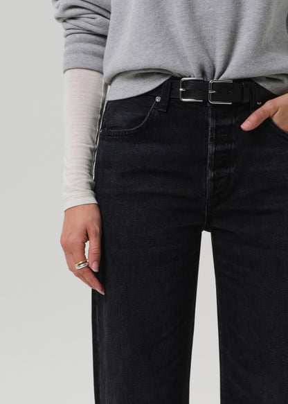 Person wearing black jeans with a gray sweater and white shirt underneath on a light gray background