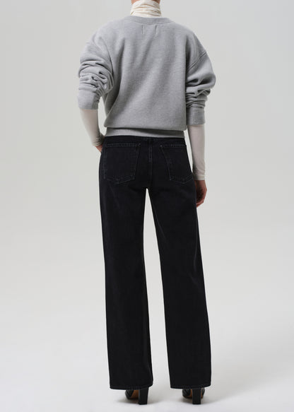 Person wearing a gray sweater and black pants on a white background