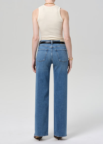 Person wearing blue jeans and a beige top on a white background