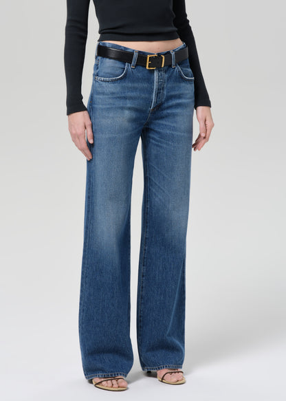 Person wearing a black long-sleeve top and blue jeans on a plain background