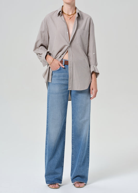 Person wearing a plaid shirt and blue jeans on a grey background