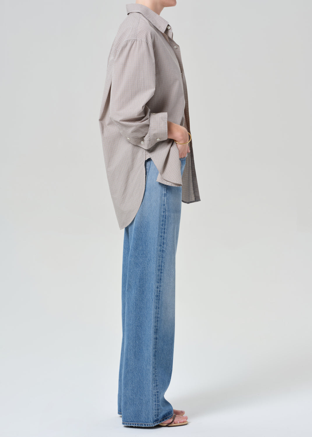 Person wearing a plaid shirt and blue jeans on a grey background