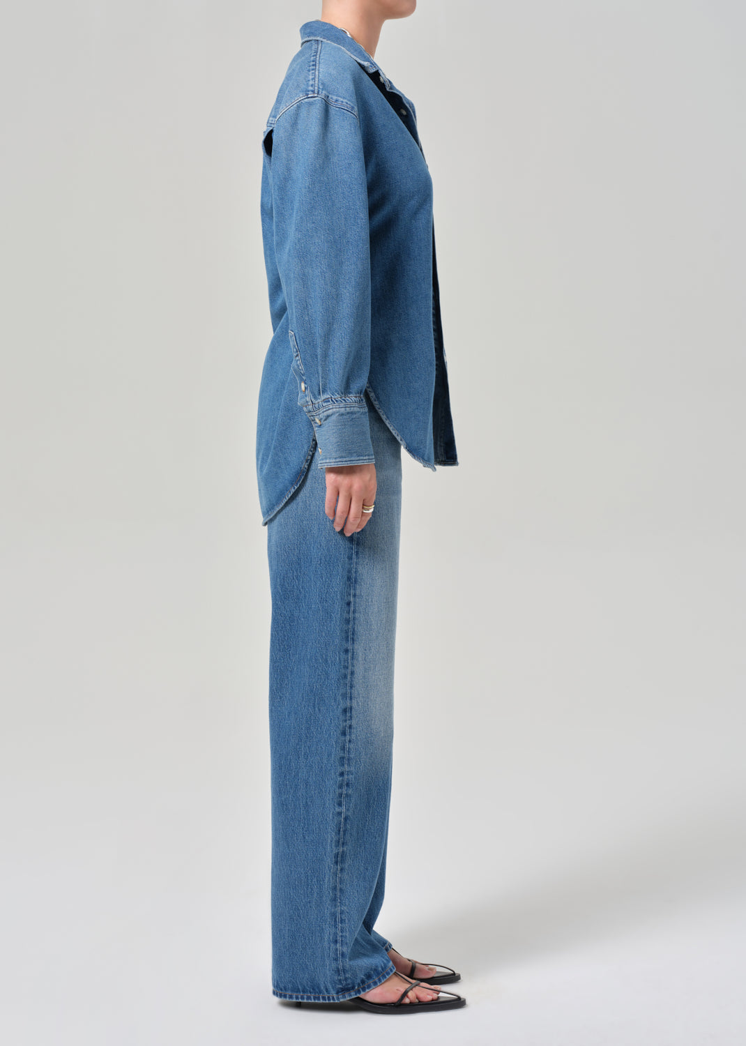 Person wearing a blue denim jacket and jeans on a white background