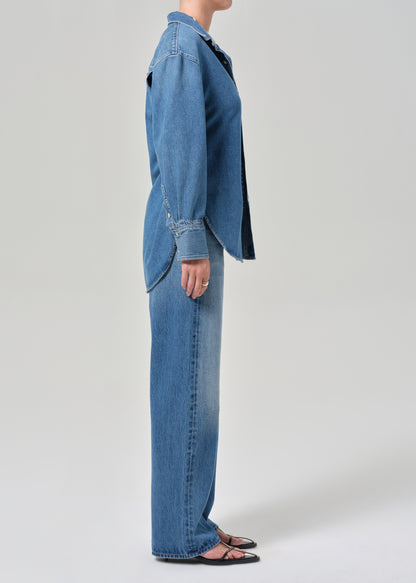 Person wearing a blue denim jacket and jeans on a white background