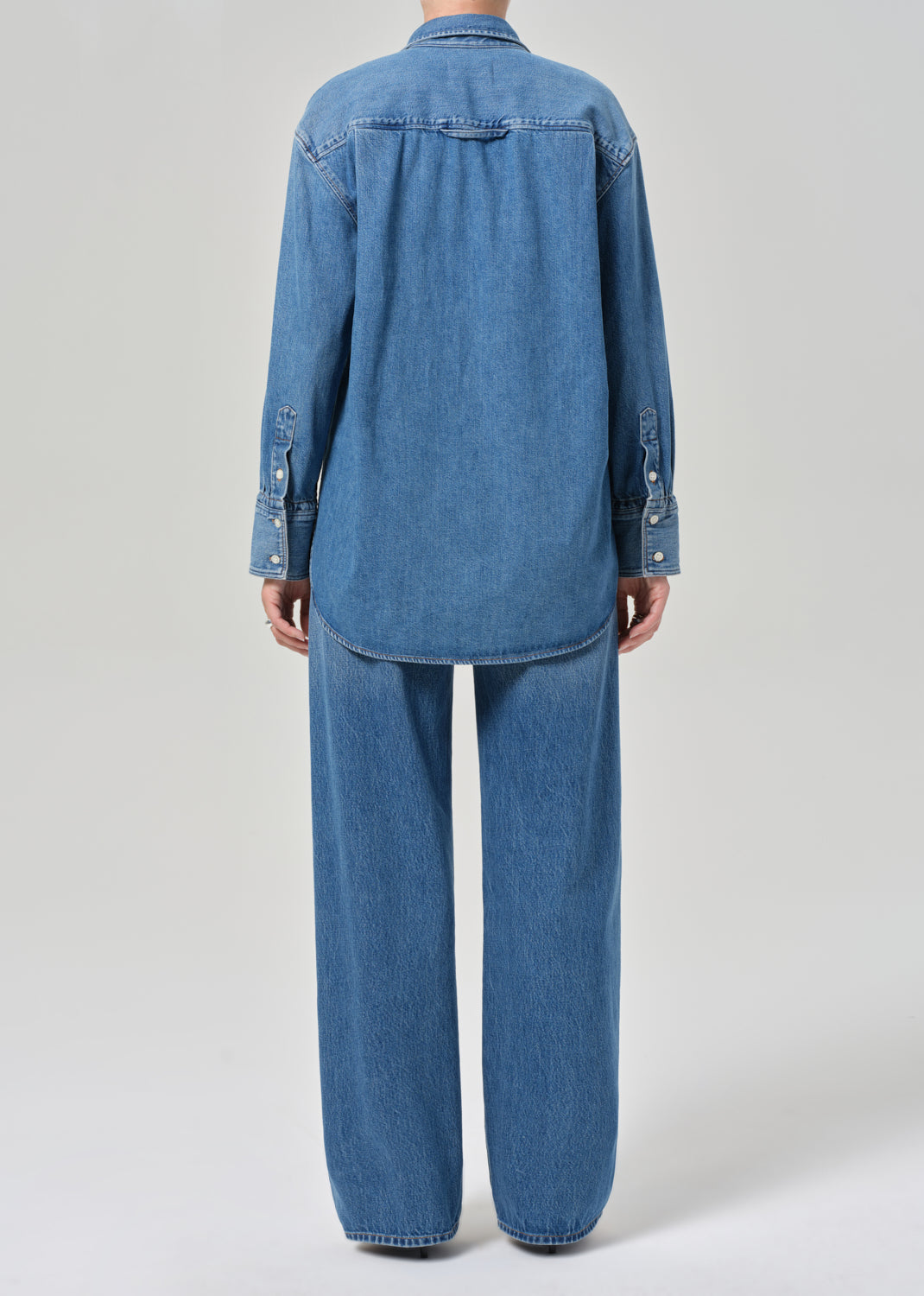 Person wearing a blue denim outfit on a light gray background