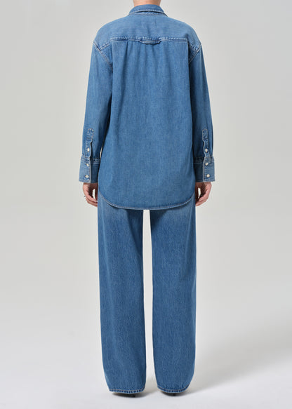 Person wearing a blue denim outfit on a light gray background