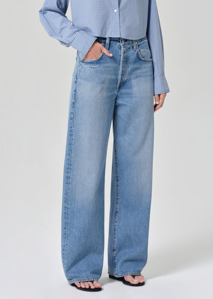 Person wearing a blue plaid shirt and jeans on a grey background