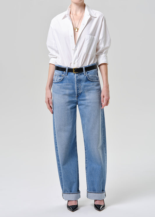 Person wearing a white shirt and blue jeans on a plain background