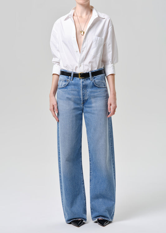 Person wearing a white shirt and blue jeans on a plain background