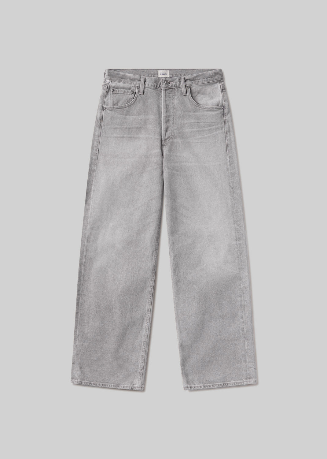 Light grey baggy jeans with subtle fading and whiskering, a classic five-pocket design, belt loops, and button and zipper closure, front flat lay view on a grey background.