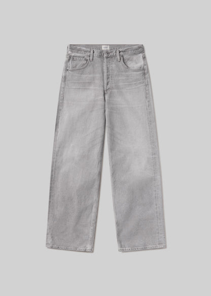 Light grey baggy jeans with subtle fading and whiskering, a classic five-pocket design, belt loops, and button and zipper closure, front flat lay view on a grey background.