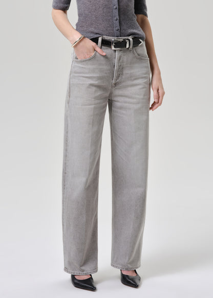 Person wearing a gray cardigan and light gray jeans on a grey background