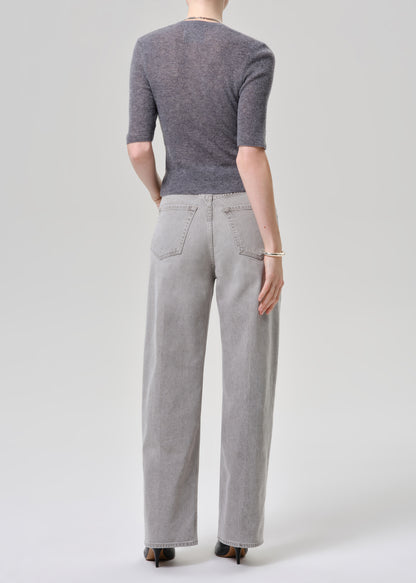 Person wearing a gray cardigan and light gray jeans on a grey background