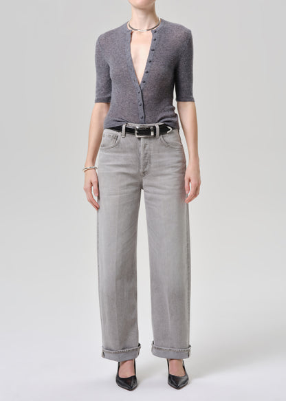 Person wearing a gray cardigan and light gray jeans on a grey background