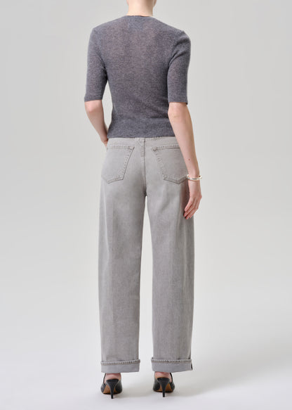 Person wearing a gray cardigan and light gray jeans on a grey background