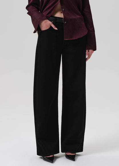 Person wearing a burgundy top and black pants on a white background