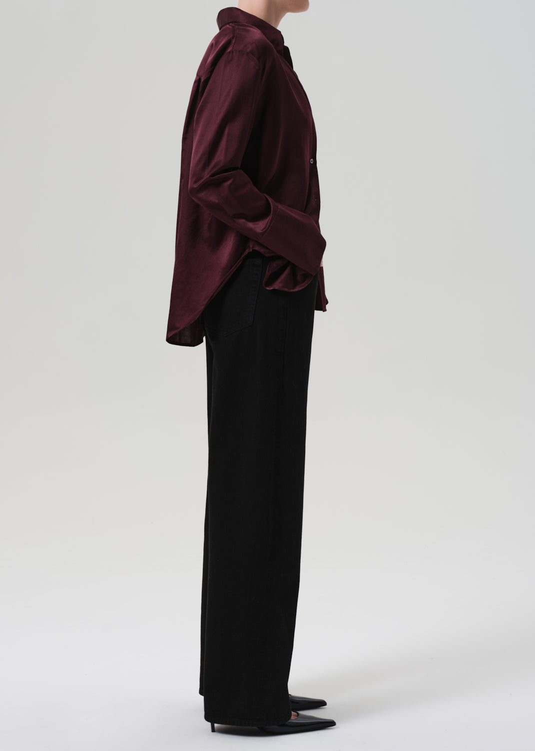 Person wearing a burgundy shirt and black pants on a white background