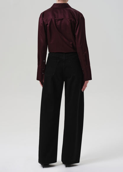 Person wearing a burgundy shirt and black pants on a white background