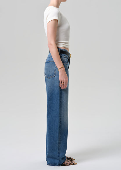 Person wearing blue jeans and a white crop top on a plain background