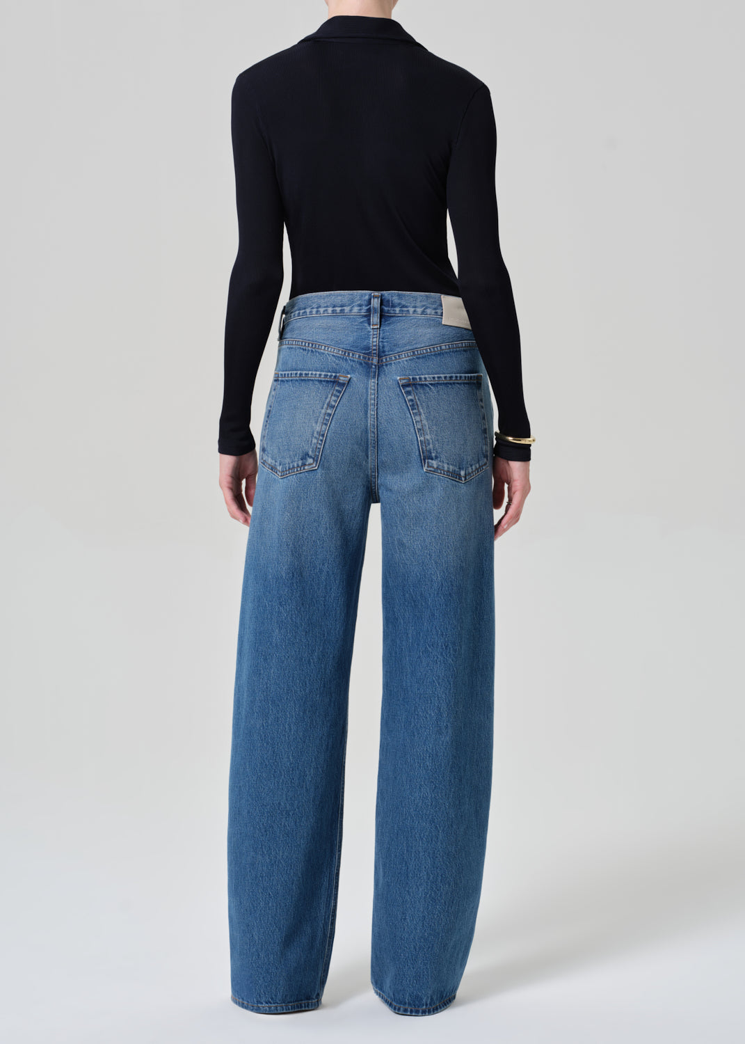 Person wearing blue jeans and a navy long-sleeve shirt on a white background