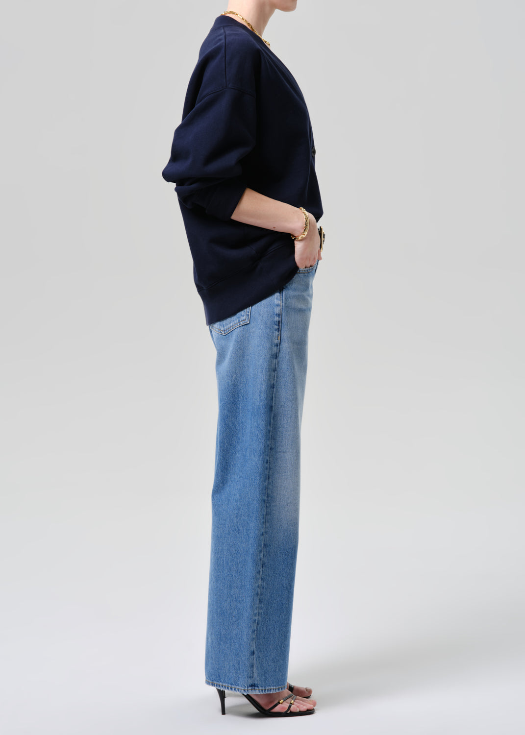 Person wearing a navy sweater and blue jeans on a grey background