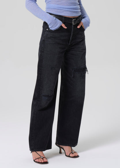 Person wearing black wide-leg jeans and a light blue sweater on a white background