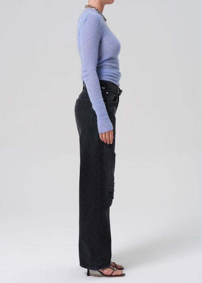 Person wearing a light blue sweater and black pants on a white background